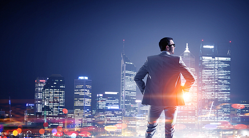 Young elegant businessman against night city background