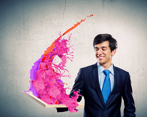 Handsome businessman holding frame with colorful splashes