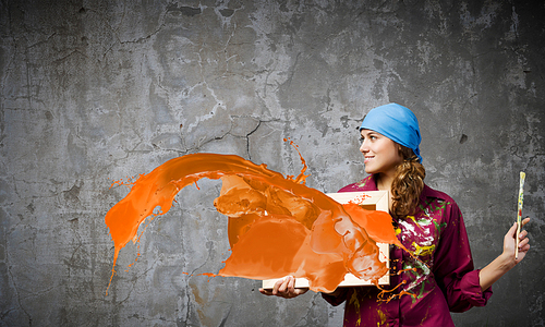 Young woman painter holding frame with colorful splashes