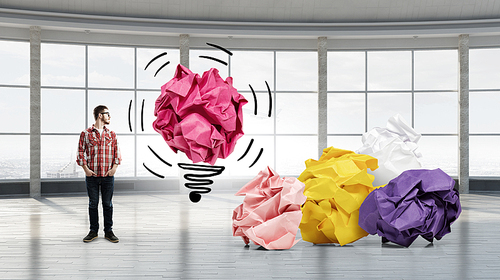 Young man in modern interior and paper balls as symbol of creativity