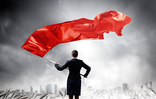 Young determined businesswoman with red flag in hands