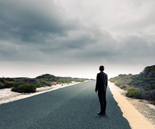 Back view of businessman standing on road and looking far away