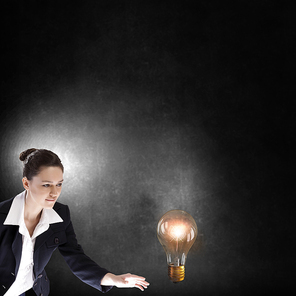 Young businesswoman catching glass light bulb with fingers
