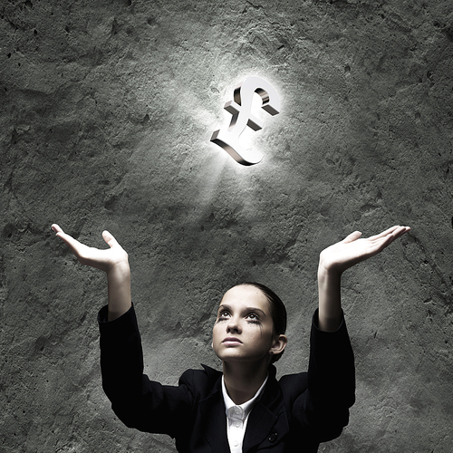 Young businesswoman praying for pound symbol above head