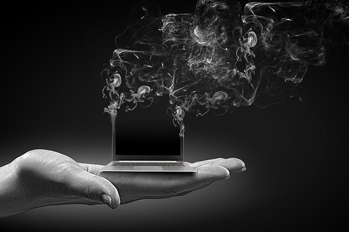 Human hand holding burning laptop on palm