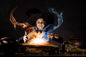 Little Halloween witch reading conjure from magic book