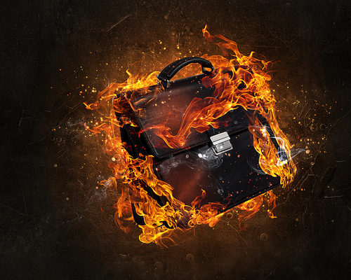 Black briefcase in fire flames on dark background