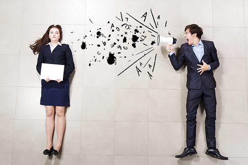 Aggressive businessman shouting at colleague with megaphone