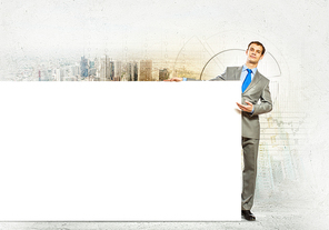 Businessman with blank banner standing against urban scenic. Place for text