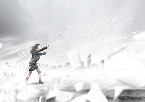 Young determined businesswoman walking against strong wind