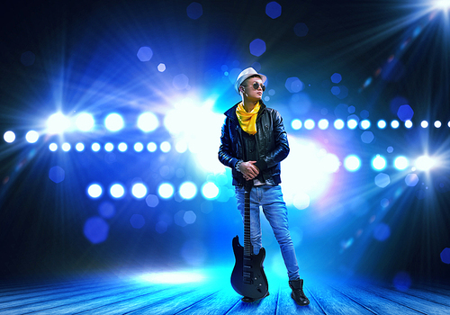 Young man, rock musician in jacket with guitar
