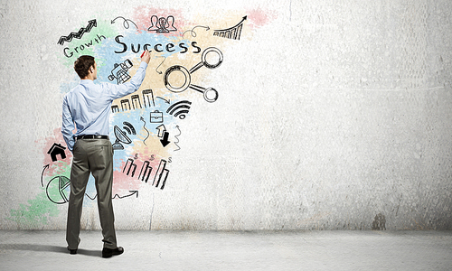 Back view of businessman drawing business sketches on wall