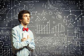 Image of thoughtful male student holding notebook in classroom