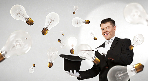 Young cheerful businessman making tricks with magic hat