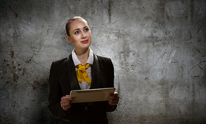 Young pretty businesswoman against grey background using tablet pc