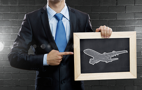Close up of businessman holding wooden frame with airplane sign