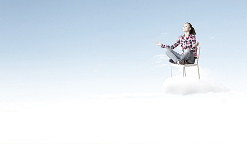 Young woman sitting on chair and meditating