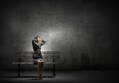 Young frustrated businesswoman covering ears with hands and screaming