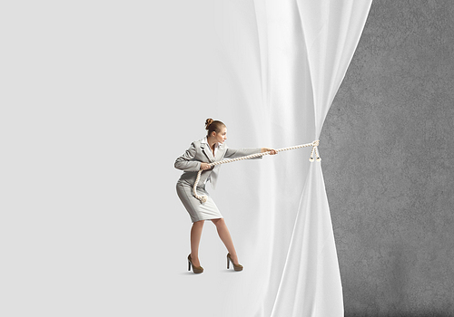 Young businesswoman pulling curtain with rope. Place for text