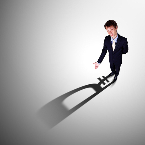 Image of a business man with a shadow shaped as a currency sign