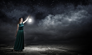 Young woman with lantern walking in darkness