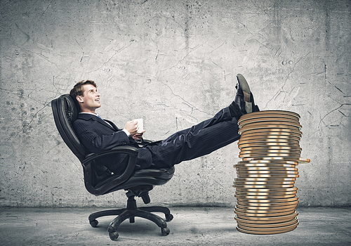 Young confident businessman sitting in chair with legs on cent coin