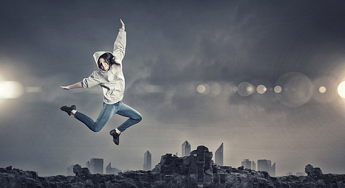 Young woman dancer jumping in spotlights on dark background