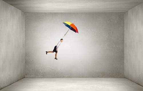Young businesswoman flying high in sky on umbrella