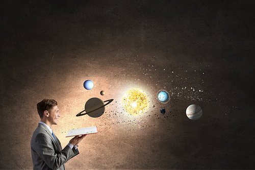 Young businessman with book and planets of space spinning around