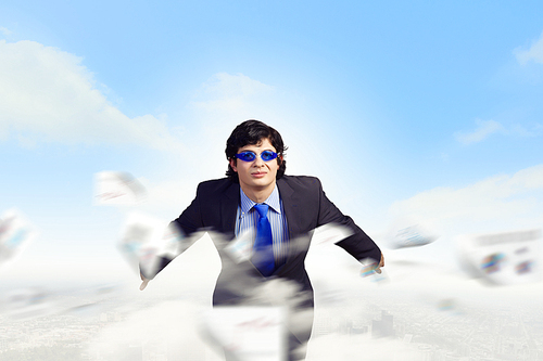 Image of young businessman in goggles jumping from top of building