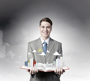 Businessman holding opened book with construction model on pages