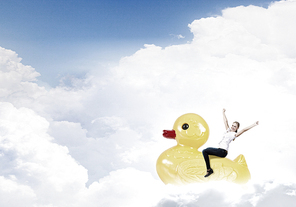 Young happy businesswoman riding yellow rubber duck