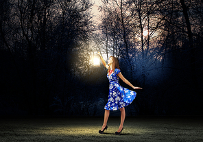 Young woman in blue dress walking in night wood
