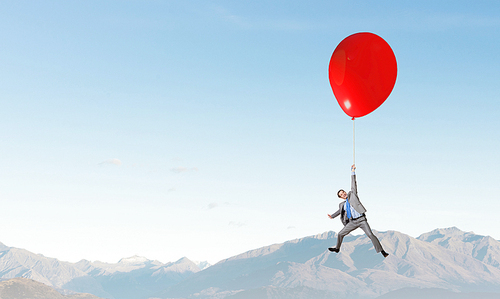 Young successful businessman flies on colorful balloon