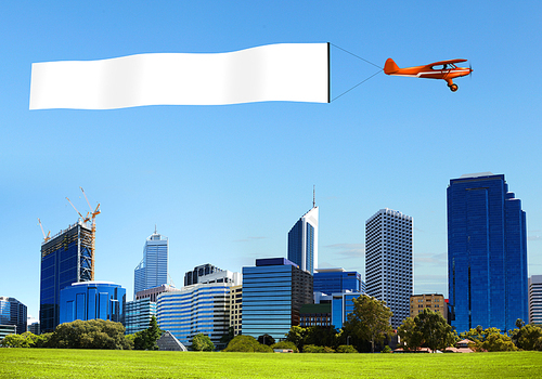 Plane in the sky above the city with blank flag