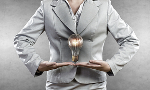 Young businesswoman presenting glass glowing light bulb in her hands