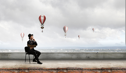 Young businessman sitting in chair with old book in hands