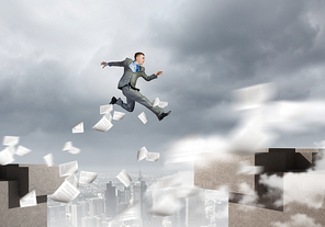 Young businessman jumping over bridge gap. Risking in business