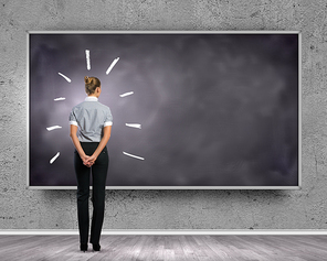 Rear view of businesswoman looking at chalkboard