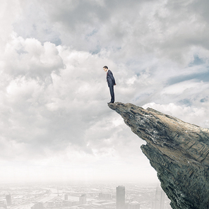 Young businessman standing on edge of rock mountain