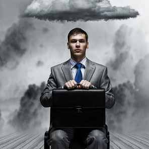 Young businessman sitting on chair with suitcase on knees