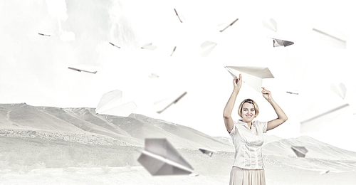 Young carefree woman with paper plane in hands