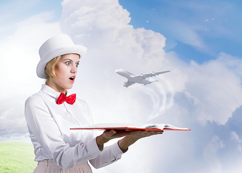 Young woman in white hat with opened book in hands and airplane flying out