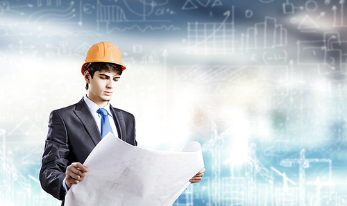 Young man engineer in helmet examining construction project