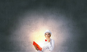 Young woman in white hat with opened red book in hands