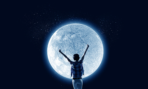 Rear view of young woman with hands up looking at moon in sky