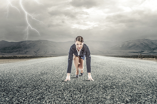 Young determined businesswoman standing in start position ready to compete