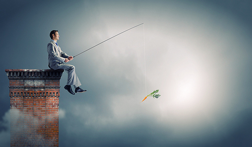 Businessman sitting on top of building and fishing with rod