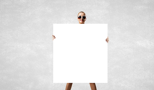 Young woman in sunglasses showing white blank banner