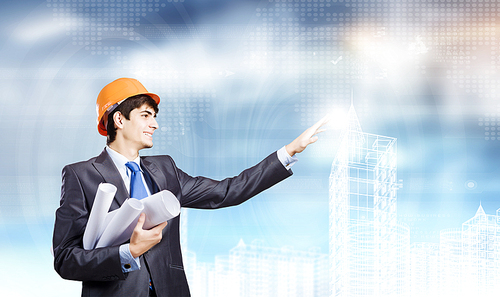 Young man engineer in helmet touching icon of media screen